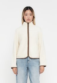 Fleece jack in crème, met een hoge kraag en een bruine rits, met een cropped ontwerp en wijde mouwen, verfraaid met bruine accentlijnen.