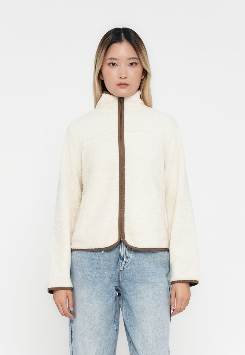 Fleece jack in crème, met een hoge kraag en een bruine rits, met een cropped ontwerp en wijde mouwen, verfraaid met bruine accentlijnen.
