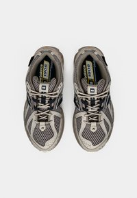 Grå mesh-sneakers med ett texturerat ovandel, svarta detaljer och kontrasterande snören. Har en vadderad sula och en logga på tungan.