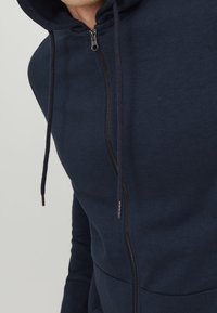 Námořnická zipová mikina s podšívkou kapuce, šňůrkami a předními kapsami. Vyrobena z měkké, texturované látky.