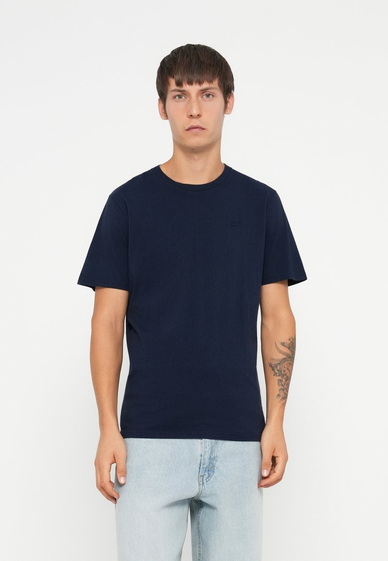 T-shirt in cotone blu navy con scollatura rotonda e maniche corte. Presenta un logo discreto sul petto e una texture morbida.
