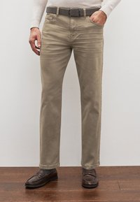Chino beige in cotone con taglio dritto, tasche frontali e cintura. Texture liscia, design minimale, abbinati a mocassini marrone scuro.