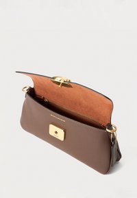 Sac à bandoulière en cuir marron avec rabat ouvert montrant l'intérieur en daim orange, une poche zippée dorée, une quincaillerie dorée et une étiquette Coach.