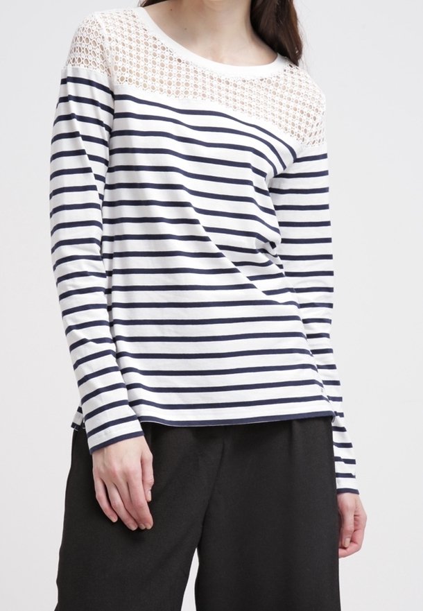 Långärmad skjorta med marinblå och vita horisontella ränder. Spetsdetalj vid ringningen. Mjuk tyg med en avslappnad passform. Kombineras med svarta byxor.