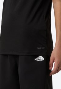 Μαύρο αθλητικό πουκάμισο με λογότυπο "FLASHDRY", συνδυασμένο με μαύρο σορτς που φέρει το λευκό λογότυπο "THE NORTH FACE". Ομαλή υφή, εφαρμοστή σχεδίαση.