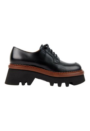 Chaussure noire en cuir à lacets avec une semelle plateforme noire épaisse et une bordure brunâtre en forme d'ondulations sur la semelle intercalaire, vue de profil.