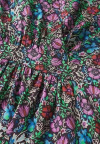 Tissu de robe fleurie présentant un fond noir, des fleurs multicolores en violet, bleu, rouge et vert avec une texture froncée et un motif détaillé.