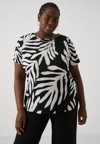 Short-sleeve top featuring a black and white leaf pattern, made from textured fabric, with a relaxed fit and rounded hemline.