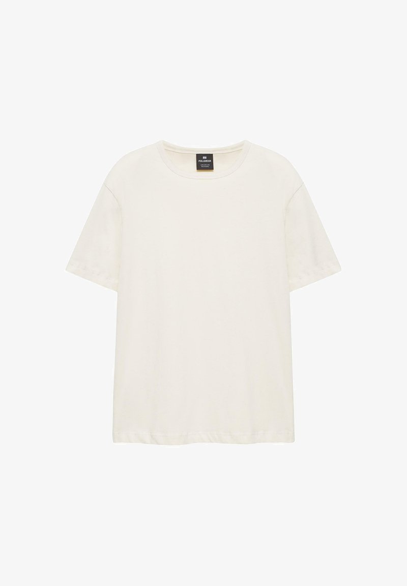 T-shirt crème à manches courtes avec col rond et une étiquette de marque noire à l'intérieur du col, présenté sur un fond blanc.