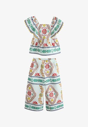 Kinder-Zweiteiler mit weißem Hintergrund, bunten Blumen- und geometrischen Mustern in Rot, Gelb, Grün und Blau, Flatterärmeln und weiten Hosenbeinen.