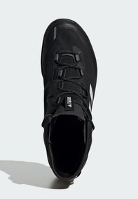 Czarne buty trekkingowe z siateczkową cholewką, zaokrąglonym noskiem, teksturowanymi panelami i wyraźnym systemem sznurowania. Zawiera metkę z logo na języku.