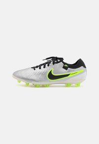 Nike Tiempo fodboldstøvler med et sølvfarvet syntetisk overdel, sorte accenter, neon grøn logo og lysegrønne stifter på en hvid sål.