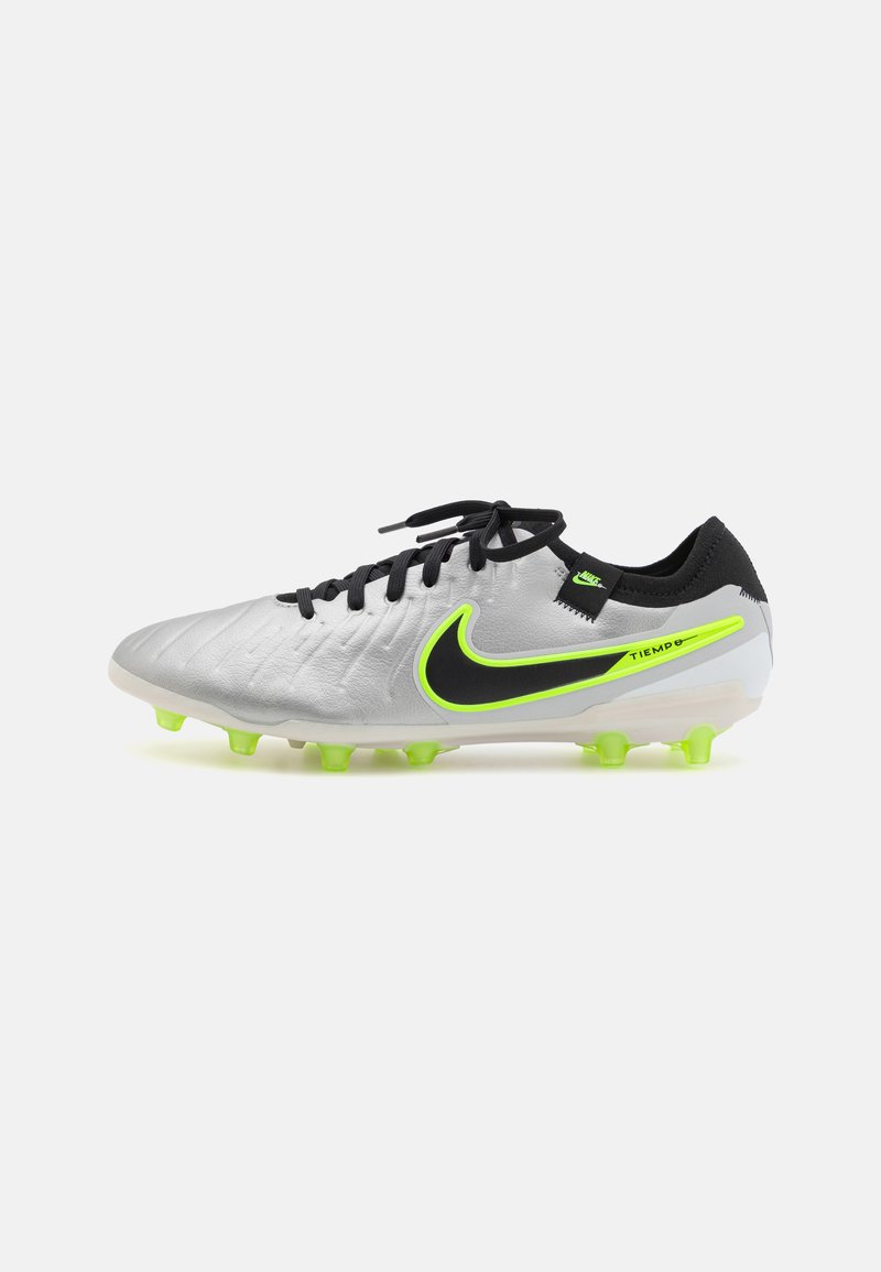 Nike Tiempo fodboldstøvler med et sølvfarvet syntetisk overdel, sorte accenter, neon grøn logo og lysegrønne stifter på en hvid sål.