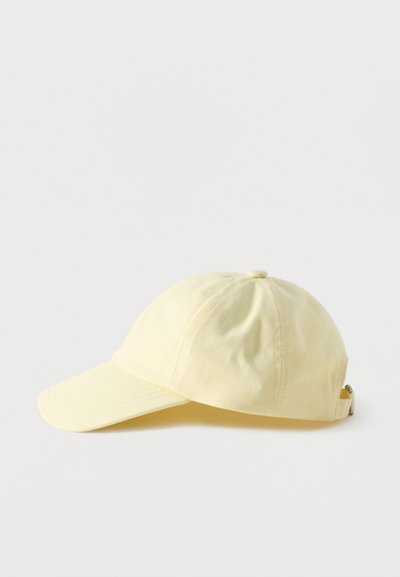 Hele kollane puuvillane pesapalli nokamüts kõvera äärega ja reguleeritava rihmaga tavalise valge taustaga.