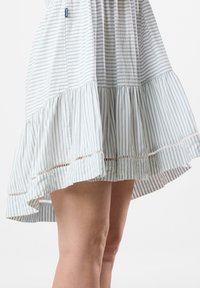 Gestreiftes Kleid in hellen Pastellfarben mit weit schwingendem Saum, Spitzenakzenten und leichtem Stoff. Das Design umfasst dünne vertikale Streifen.
