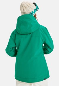 Groene waterdichte jas met een capuchon, voorzien van lange mouwen en een relaxte pasvorm. Gladde textuur met een eenvoudig ontwerp en geen zichtbare patronen.