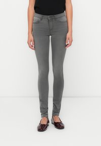 Jeans ajustados grises con una cinturilla alta, diseño de cinco bolsillos y un tejido elástico sutil, combinados con bailarinas burdeos brillantes.