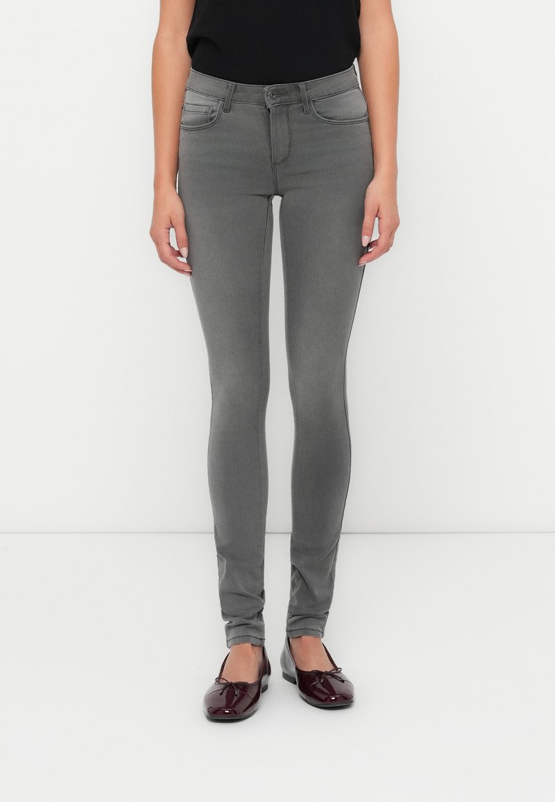 Jeans ajustados grises con una cinturilla alta, diseño de cinco bolsillos y un tejido elástico sutil, combinados con bailarinas burdeos brillantes.
