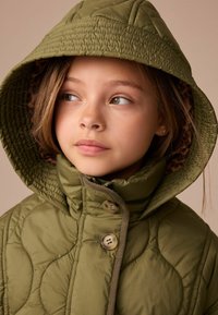 Olivgrüne Steppjacke mit Kapuze, ausgestattet mit einem Futtermaterial im Leopardenmuster, zwei Knöpfen und strukturierten Designdetails.
