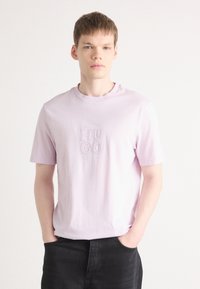 Lys lilla bomulds t-shirt med korte ærmer og rund hals, prydet med broderet "HUGO" logo i en kontrasterende mørkere nuance.