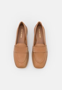 Mocassins en cuir tan avec un embout carré, ornés d'une sangle décorative avec des clous en métal, texture lisse et semelle intérieure douce.