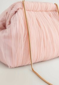 Różowa torebka z tiulu o plisowanym wzorze, miękkiej teksturze i złotym łańcuszku. Posiada zgromadzony górny element i zaokrąglony kształt.