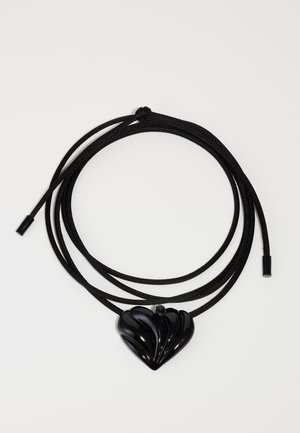 Black heart pendant on a sleek black cord. The pendant features a shiny, textured design with raised ridges and a smooth finish.