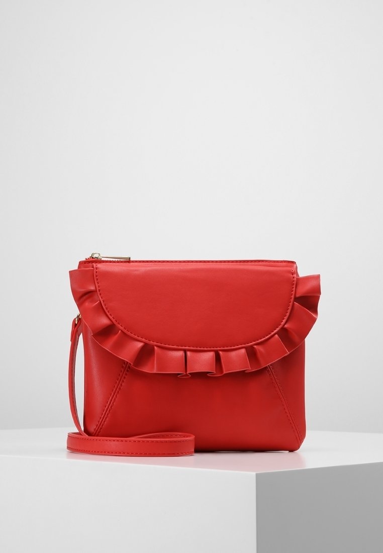 Rød læder crossover taske med en bølget flap, lynlåslukning og en aftagelig rem. Glat tekstur og vinkelret design.