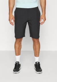 Schwarze Shorts aus leichtem Stoff, mit geradem Schnitt, vorderem Knopfverschluss und seitlichen Taschen. Tragen mit schwarzen Schuhen und weißen Socken.