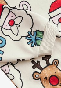 Bomulds sweatshirts med farverige tegneserie designs af julemanden, et rensdyr og snefnug. Lys beige baggrund med ribbede manchetter.