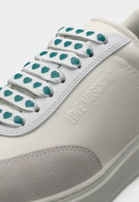 Λευκό αθλητικό παπούτσι Love Moschino με κορδόνια σε σχήμα καρδιάς σε αποχρώσεις τιρκουάζ και ανοιχτό γκρι σουέντ μύτη.