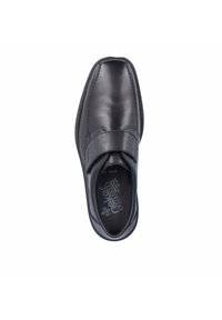 Chaussure en cuir noir avec un bout arrondi, design à enfiler et une sangle sur le coup de pied. Comprend des accents de couture et un intérieur rembourré.
