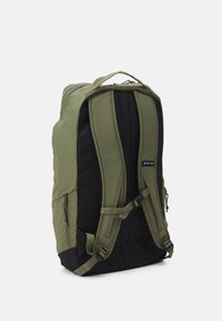 Sac à dos vert et noir doté de sangles ergonomiques, d'une conception robuste et d'une texture lisse, avec une petite étiquette affichant le nom de la marque.