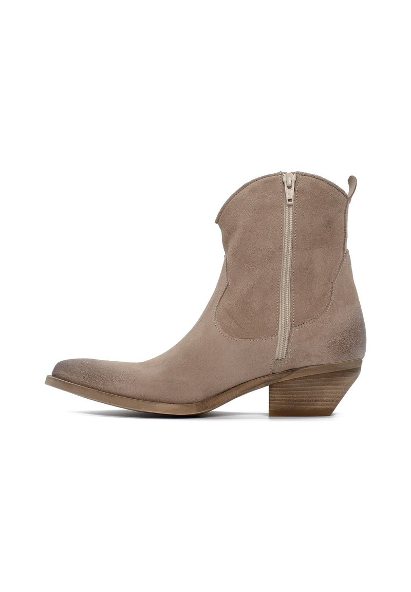 Stivaletto alla caviglia in camoscio beige con punta appuntita, cerniera laterale e tacco impilato in legno. Texture liscia e design leggermente curvo.