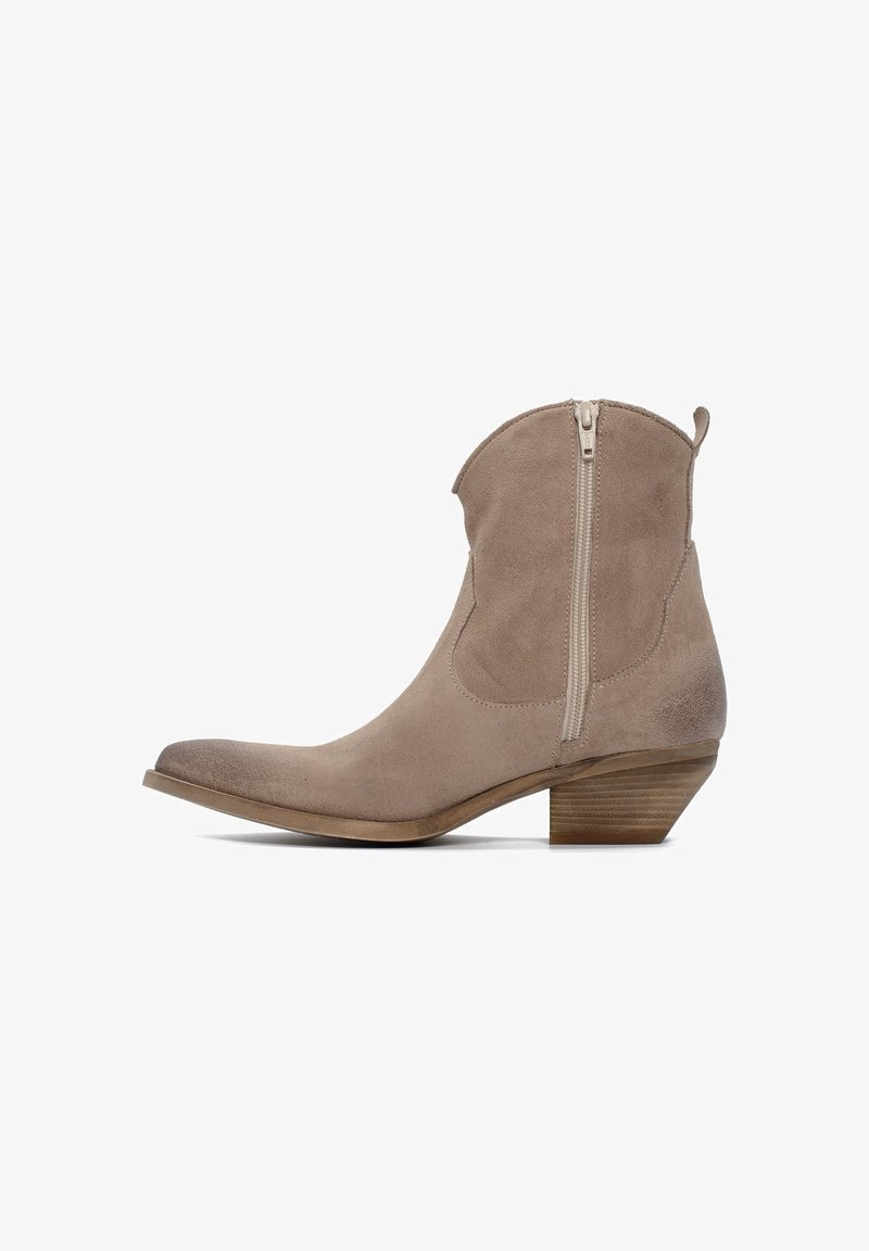 Stivaletto alla caviglia in camoscio beige con punta appuntita, cerniera laterale e tacco impilato in legno. Texture liscia e design leggermente curvo.