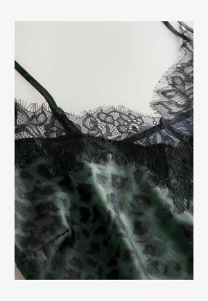 Camisole en satin vert avec des détails en dentelle noire, arborant un motif léopard. Bretelles spaghetti et détails en dentelle délicate et texturée.