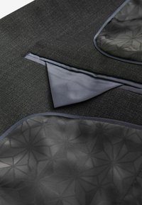 Schwarzer, strukturierter Stoff mit einer geometrisch gemusterten Taschenfutter. Verfügt über elegante, dunkle Akzente und ein scharf gefaltetes Taschendetail.