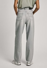 Ljusgrå denimjeans med avslappnad passform, utrustade med två bakfickor och en märkesmidja. Texturen är mjuk med minimal slitage.