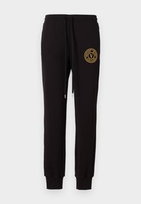 Sorte joggebukser laget av bomull med elastisk midje, med en gullbrodert logo på venstre lår og tettsittende mansjetter.