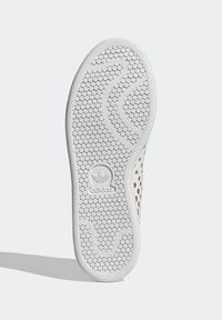 Vitt gummisul med hexagonalt greppmönster, utrustad med en logotyp och en slät kant; designad för grepp och komfort.