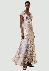 Floral maxi dress with a v-neck, ruffled sleeves, and patchwork design in light beige, blue, and floral patterns; flowing fabric texture.