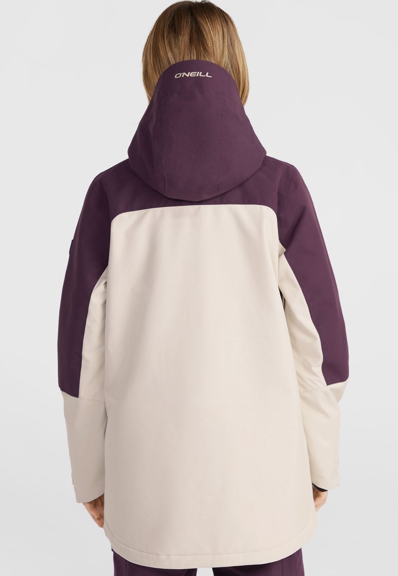 Beige und lila Jacke mit Kapuze, die ein Design mit Kontrastfarbblock aufweist. Auf dem Rücken ist ein Logo in der Nähe des Nackenbereichs zu sehen. Glatte Textur.