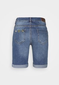 Jeansshorts i medelblå färg; har uppvikt fåll och dekorativ broderi på bakfickorna. Standard femficksdesign.