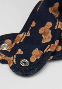 Modrá látka s potiskem medvídků, s stříbrnými patentkami a měkkou strukturou. Navrženo pro pohodlí a funkčnost.