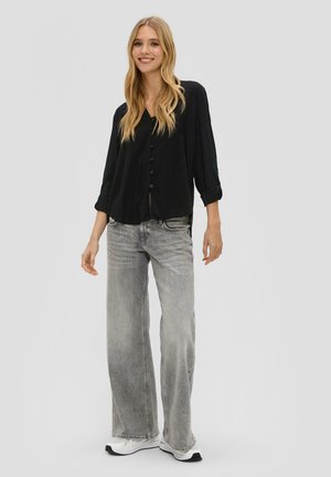 Black button-up blouse with rolled sleeves, paired with wide-legged faded grey jeans and white sneakers, featuring a relaxed fit and soft texture.