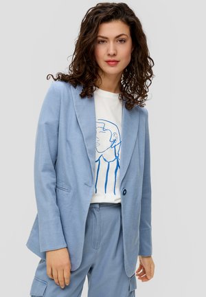 Blazer bleu clair avec un motif texturé, fermeture à un bouton, et revers cranté, associé à un t-shirt blanc avec un design en ligne bleue.