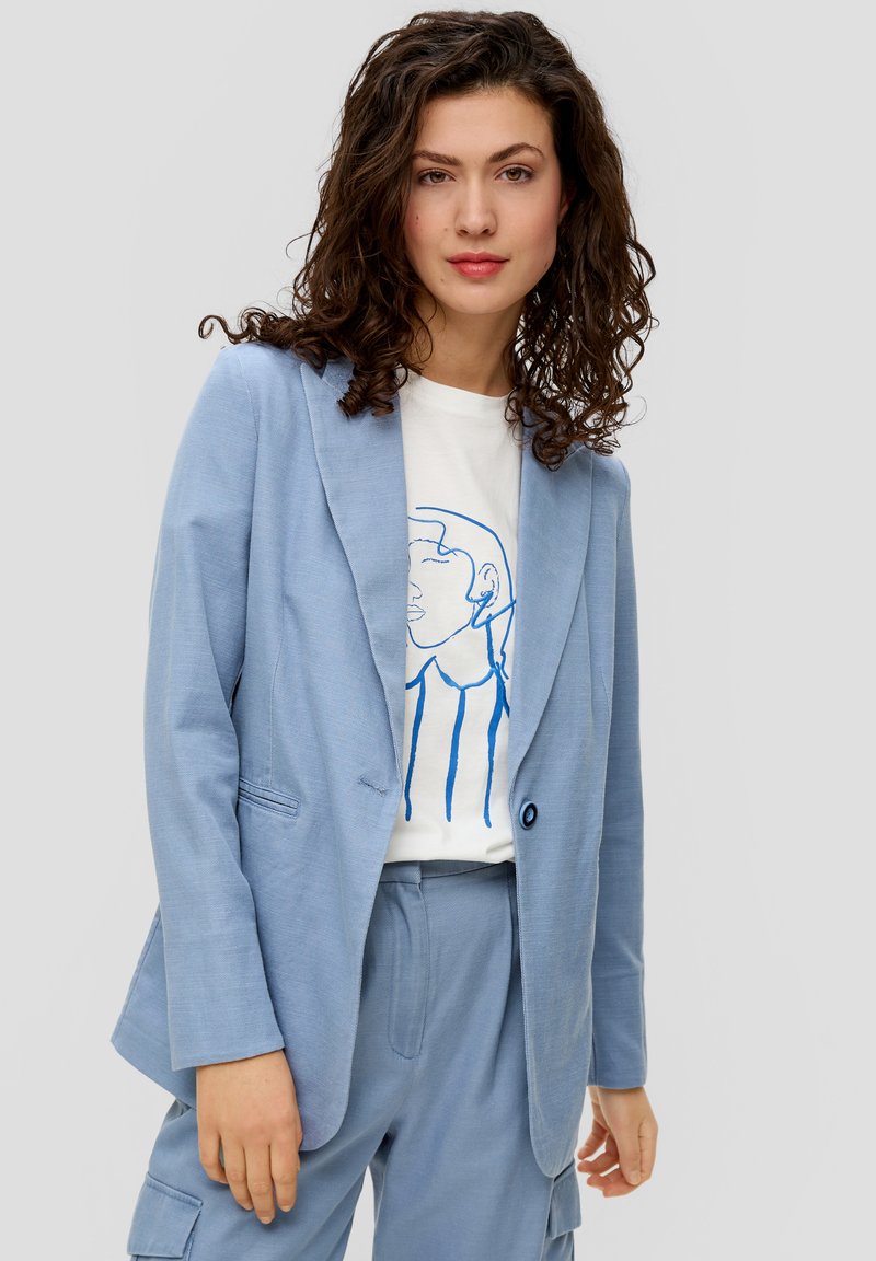 Hellblauer Blazer mit strukturiertem Muster, Ein-Knopf-Verschluss und Revers, kombiniert mit einem weißen T-Shirt mit einem blauen Linienstil-Design.