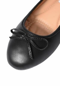 Ballerine nere realizzate in pelle texturizzata, con punta rotonda e un piccolo fiocco in tessuto sul davanti. Fodera interna liscia.