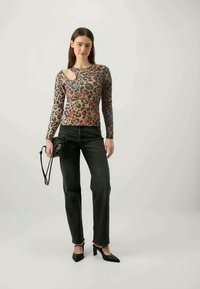Long-sleeve leopard print top with cutout at the shoulder, paired with black straight-leg jeans and black pointed-toe heels.