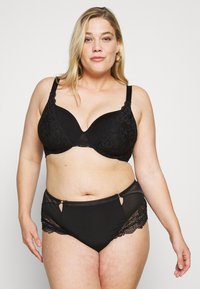 Schwarzer Spitzen-BH mit formenden Schalen und verstellbaren Trägern, kombiniert mit hochgeschnittenen schwarzen Slips, die Spitzenakzente und Ausschnittdetails aufweisen.